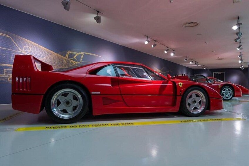 Un auto deportivo rojo en un museo con cinta de advertencia amarilla en el suelo. 1