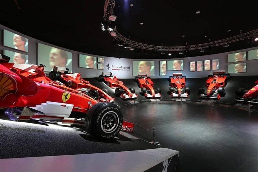 Una exposición de museo con varios autos de carreras rojos exhibidos. 3