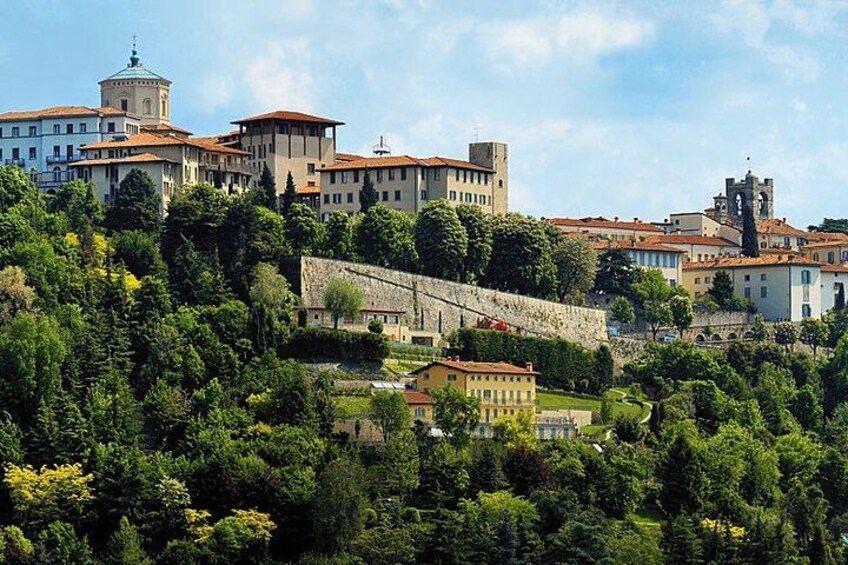 A hillside town with historic buildings, a prominent tower, and lush greenery. 2