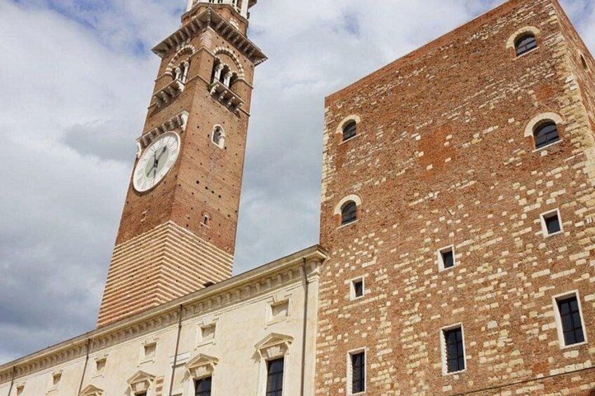 Une haute tour en briques, surmontée d’une horloge, et un bâtiment plus petit attenant, doté de nombreuses fenêtres. 3