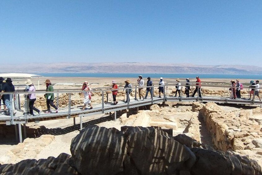 People walking on a metal bridge over a dry, rocky landscape with a clear sky. 5
