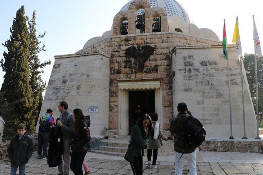 A historical building with a dome and an eagle statue. People are gathered around the entrance. 4