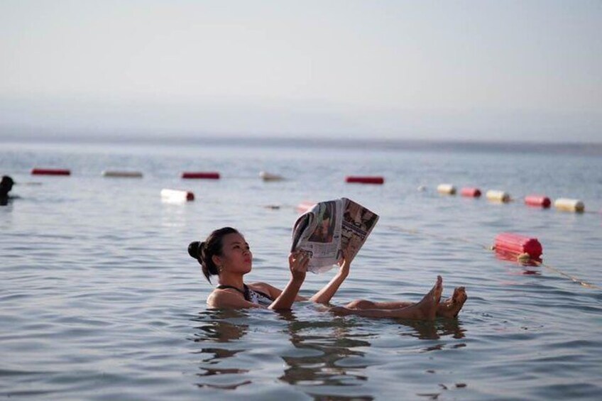 A person lying in calm water, reading a magazine. 3