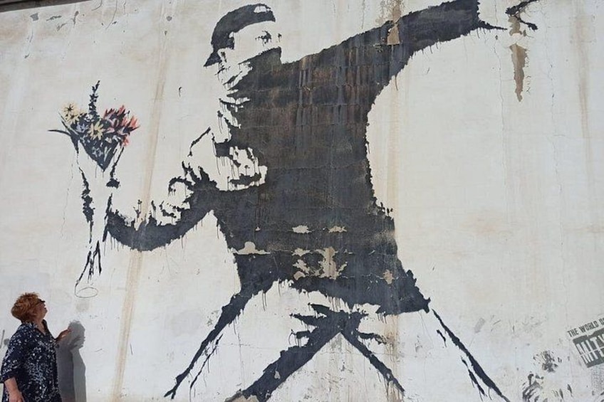 A graffiti mural of a man holding a bouquet on a wall. 4