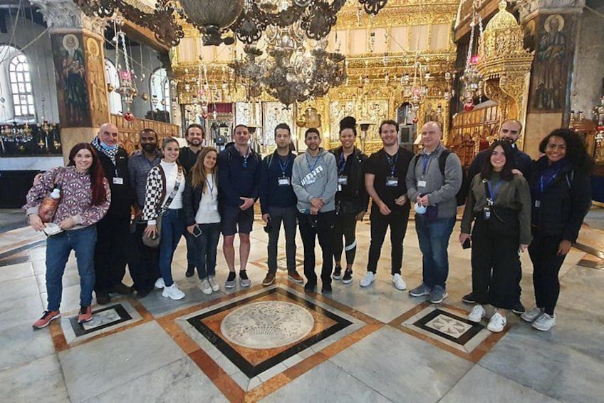 A group of people standing in a church with ornate golden decorations and a tiled floor. 5