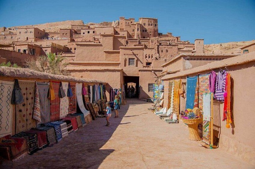 A narrow street lined with colorful textiles and traditional buildings. 2
