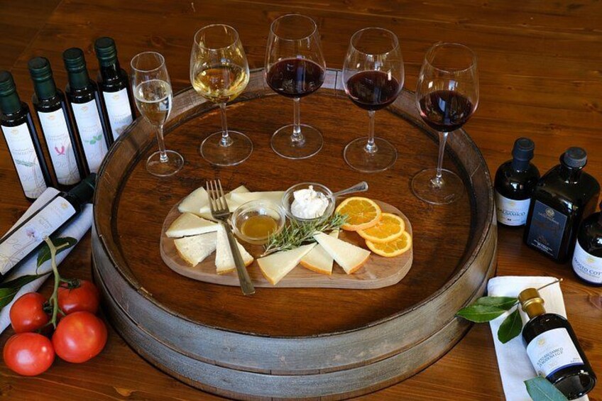 Een kaasplank met verschillende kazen, een vork en een fles wijn op een houten tafel, omringd door wijnflessen en glazen. 1