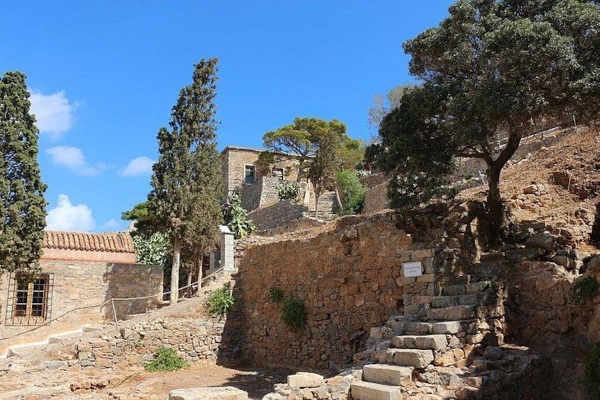A stone staircase leading up a hill, with trees and a building in the background. 5
