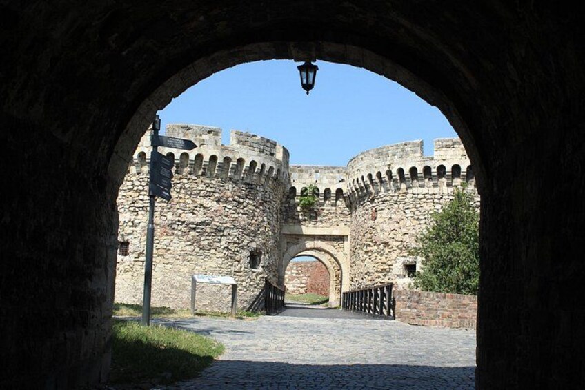 Un arco de piedra que conduce a una estructura fortificada, con cielo despejado arriba. 2