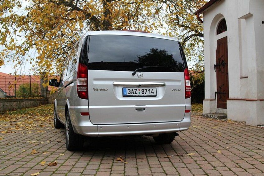 Ein silberfarbener Van steht auf einem Backsteinpflaster, umgeben von verstreuten Herbstblättern. 4
