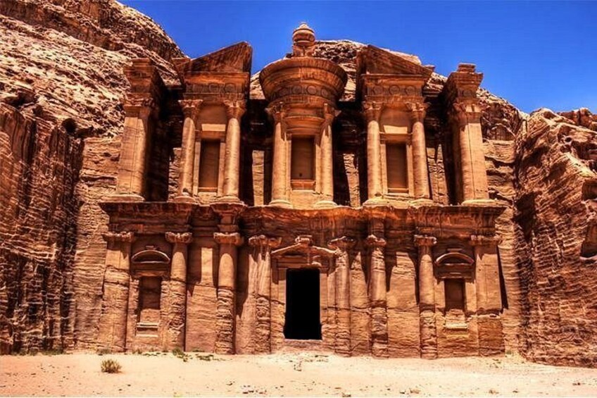 A large sandstone structure with columns and a central doorway, set against a desert backdrop. 5