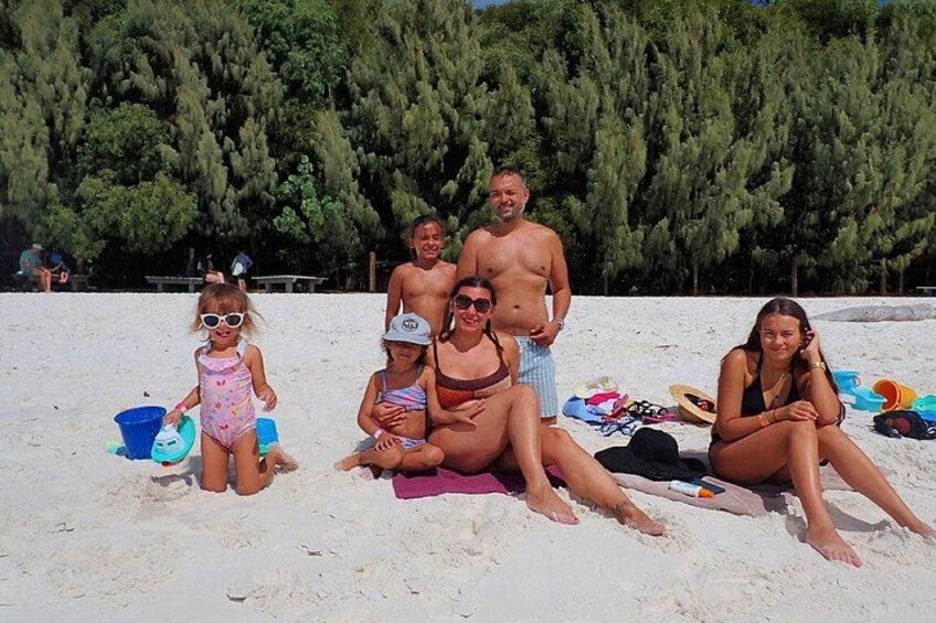Un grupo de personas en una playa arenosa con árboles de fondo. 4