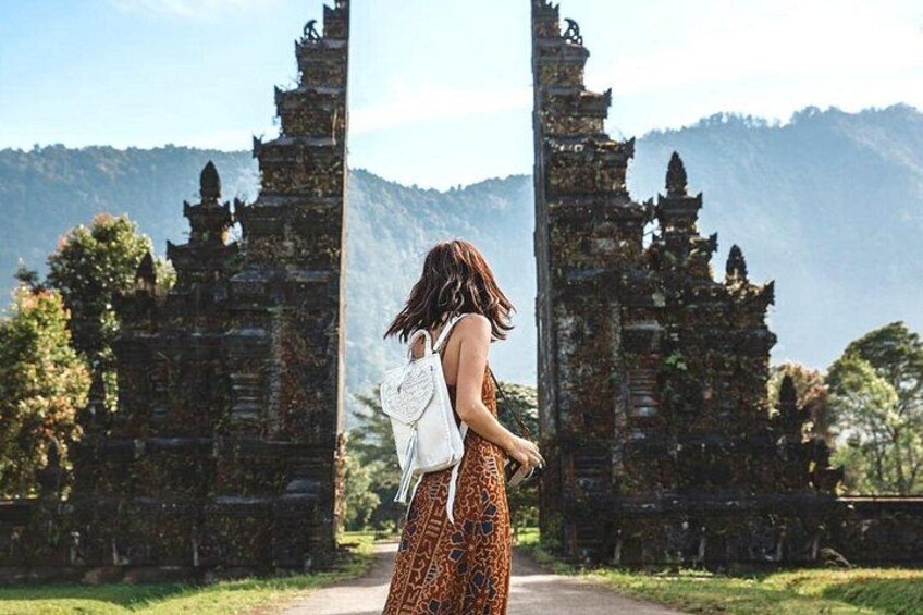 A person standing in front of ancient stone structures with a mountainous landscape in the background. 3