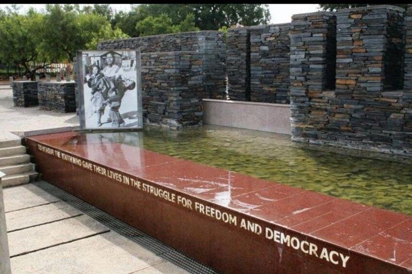 A memorial with a stone wall and a plaque, surrounded by a water feature. 2