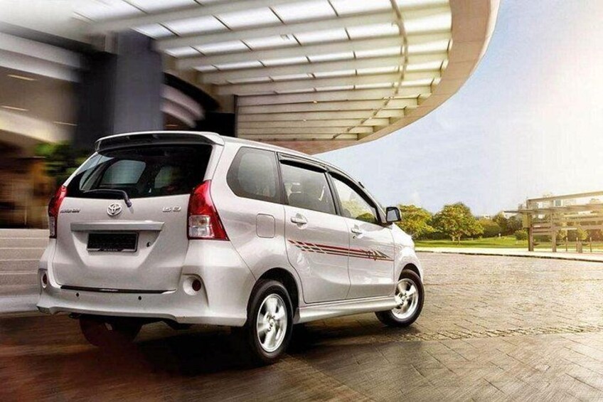 A white car parked on a paved surface with a modern building in the background. 4