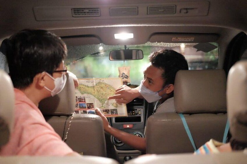 A car interior with a map on the dashboard and passengers engaged in a discussion. 1