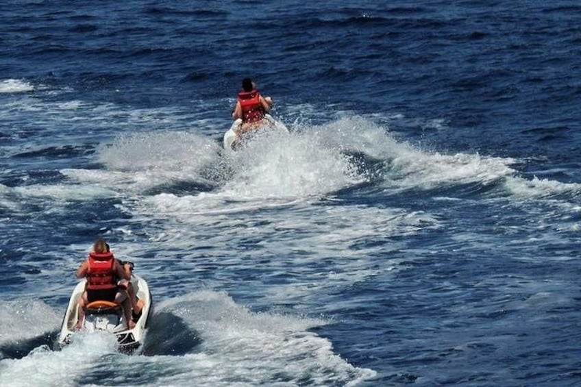Two people jet-skiing on a body of water. 2