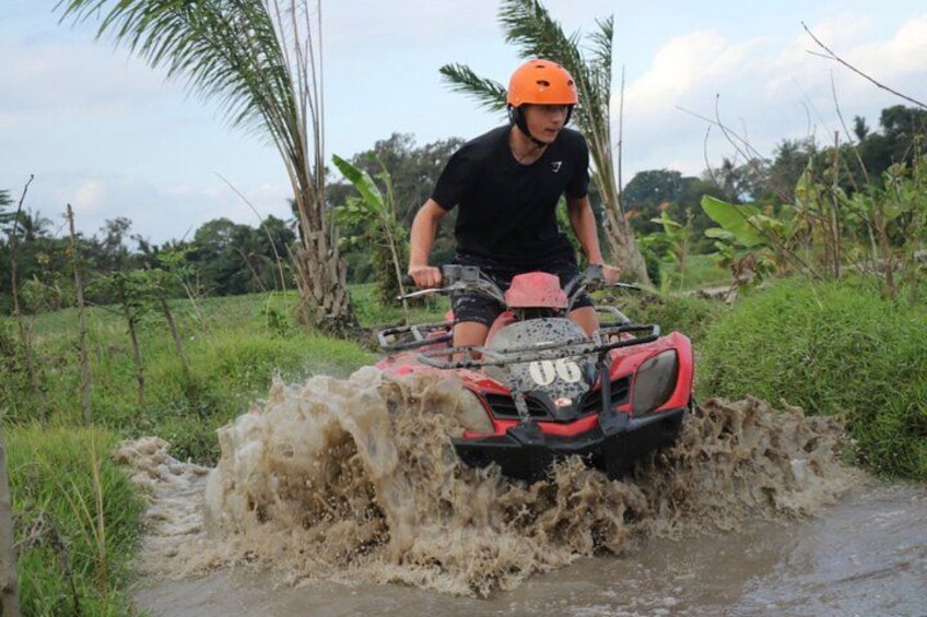 A person riding a red ATV through a muddy stream. 5