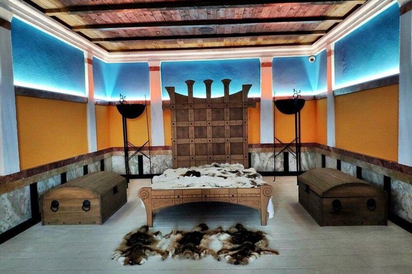Una habitación con una cama de madera, dos mesitas auxiliares y una alfombra estampada. 1