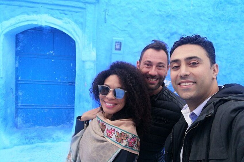 A group of people in front of a blue door with a stone archway. 3