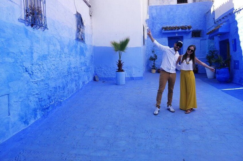 Una pareja parada en un callejón pintado de azul con macetas. 5