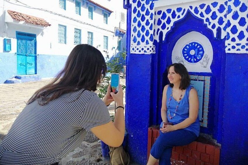 Una persona fotografiando a otra sentada en una estructura azul y blanca con un arco decorativo. 2