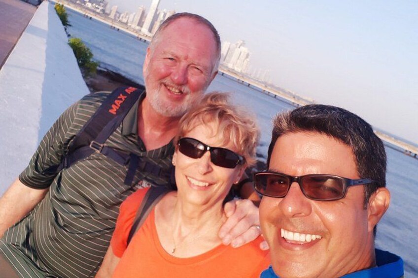 Trois personnes prennent un selfie devant un pont, avec la silhouette de la ville en arrière-plan. 5
