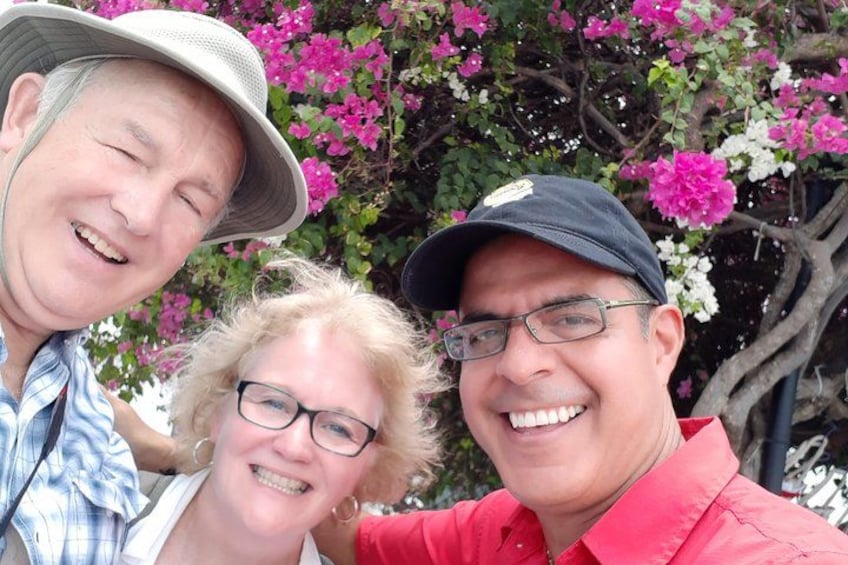 Three people in front of a tree with pink flowers. 4