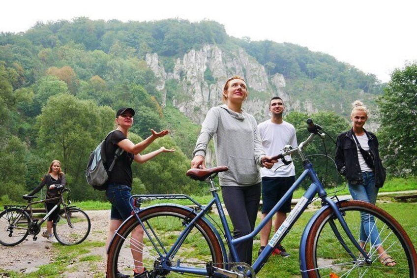 A group of people standing by bicycles in a mountainous area with greenery and rocky cliffs in the background. 5