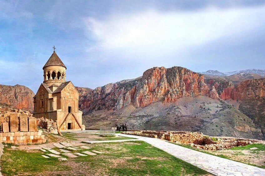 A church with a bell tower, a stone pathway, and a mountainous landscape in the background. 1