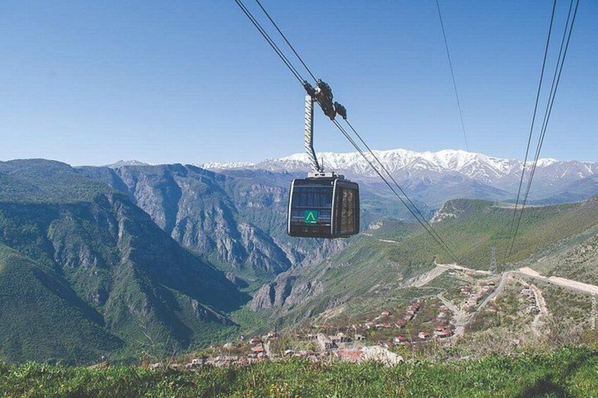 A cable car suspended over a mountainous landscape with a village below. 2