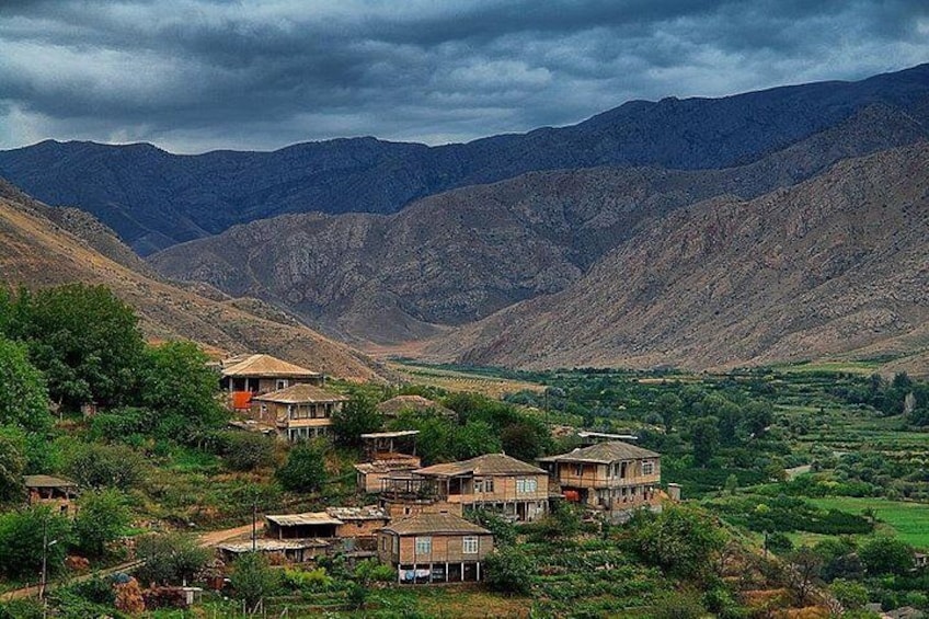 A village with houses nestled in a valley surrounded by mountains. 3