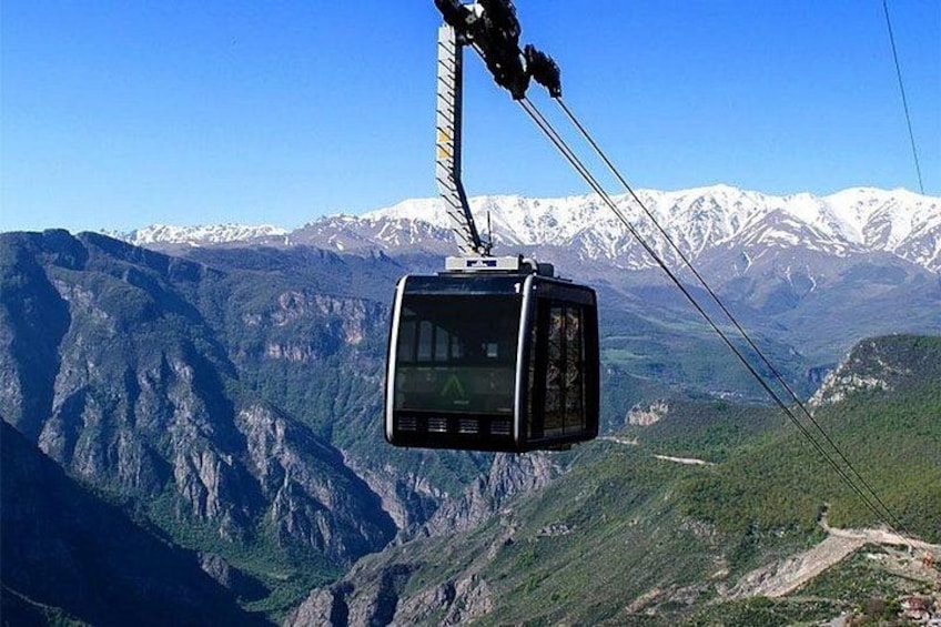 A cable car suspended over a mountainous landscape with snow-capped peaks in the background. 4