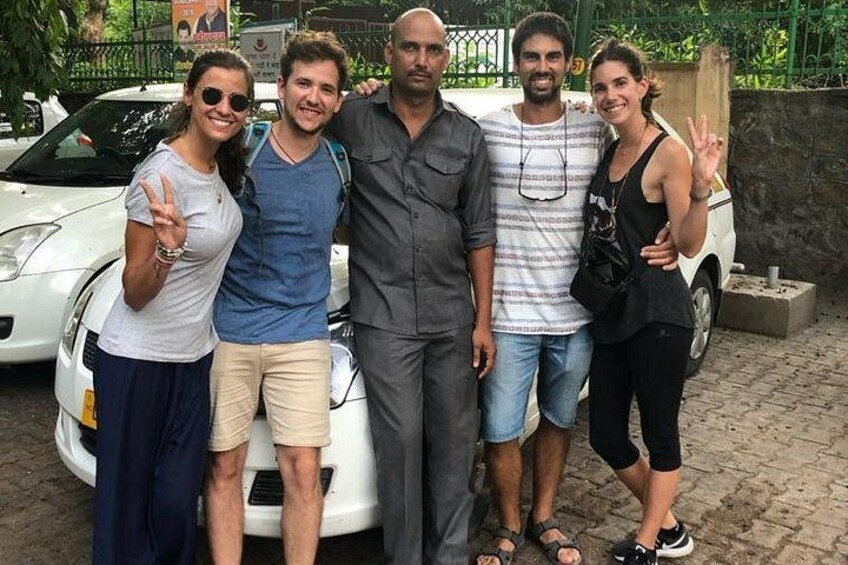 A group of people standing in front of a white car. 2