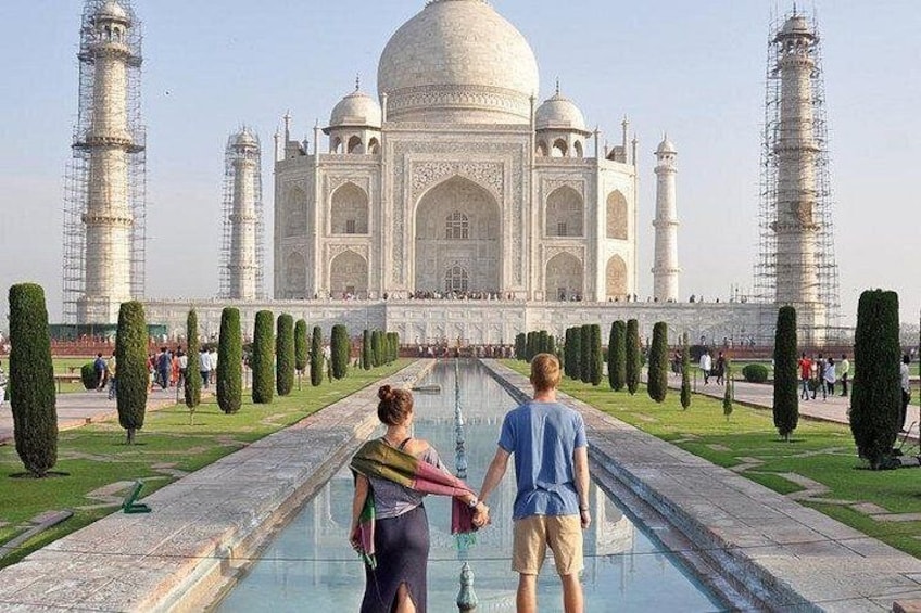 The Taj Mahal with a couple walking on the reflecting pool. 1