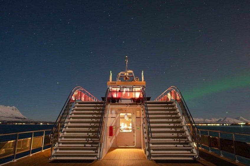 A ship's deck with a staircase leading to an upper deck, under a starry night sky with visible aurora borealis. 2
