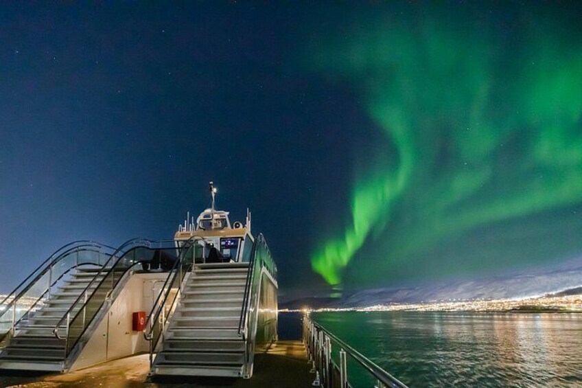 A boat with metal stairs leading to the deck, a railing, and the Northern Lights in the background. 4