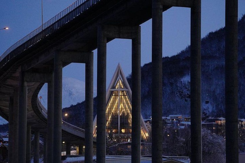 A bridge with a triangular structure illuminated at its center, surrounded by snow-covered hills. 5
