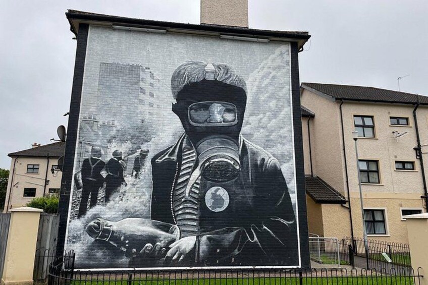 Un gran mural de una persona con máscara de gas sosteniendo una bomba, con edificios al fondo. 5