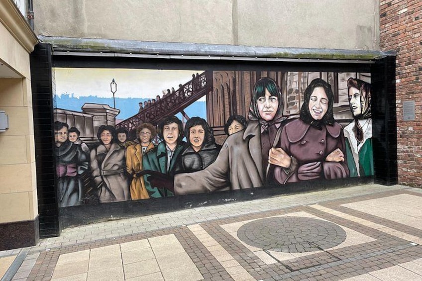 Un mural con gente pintado en una pared. 2