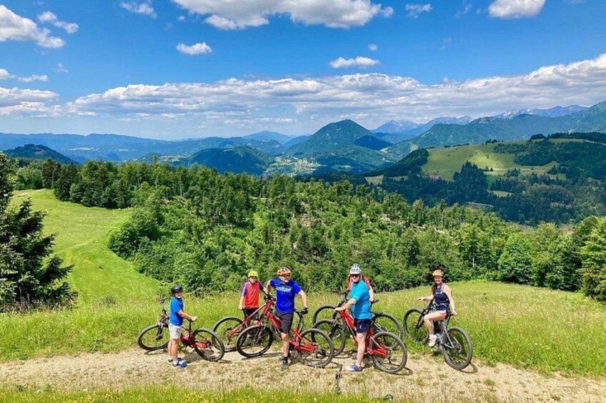 A group of cyclists on a dirt path with a mountainous landscape in the background. 1