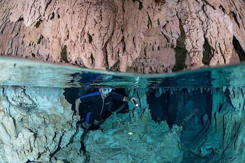 Un buzo explorando una cueva submarina con paredes rocosas y agua cristalina. 4