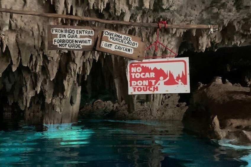 A cave interior with warning signs and a pool of water. 4