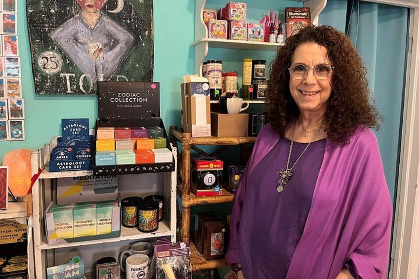 Eine Person steht vor einem Regal mit verschiedenen Gegenständen, darunter Bücher, Kartons und Gläser. 2