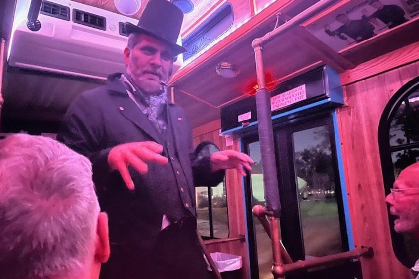 A vintage bus interior with a person gesturing, a door, and a window. 1