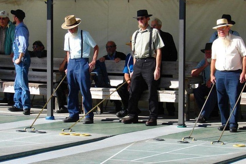 Personer som spelar shuffleboard utomhus. 5