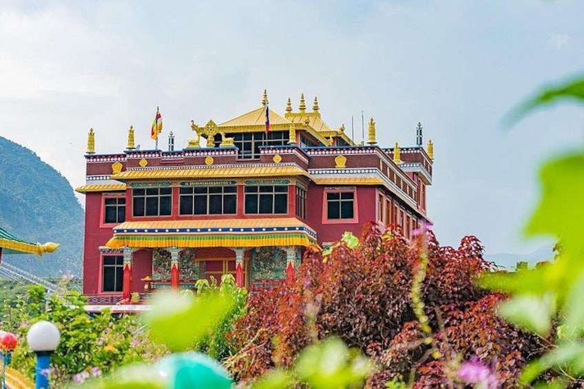 A multi-tiered building with a golden roof, surrounded by lush greenery and mountains in the background. 4