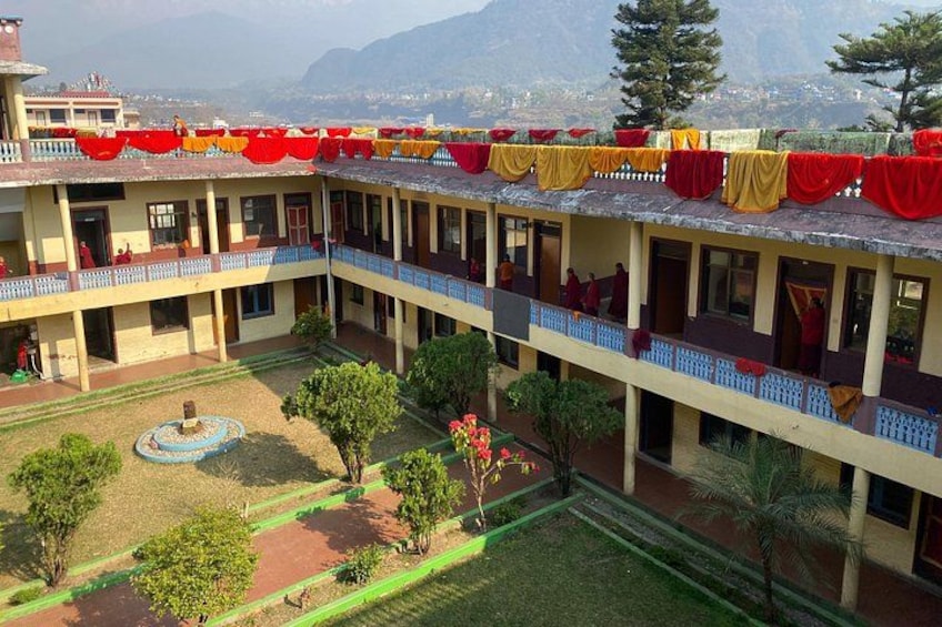A multi-story building with balconies, a courtyard, and a mountainous backdrop. 3