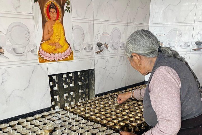 A person arranging brass bowls on a tiled floor in a room with a mural of a meditating figure. 4