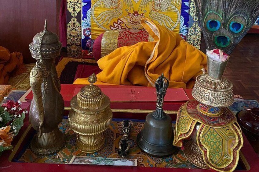 A collection of ornate Tibetan religious artifacts, including a prayer wheel, a bell, and a vase with a peacock design. 5